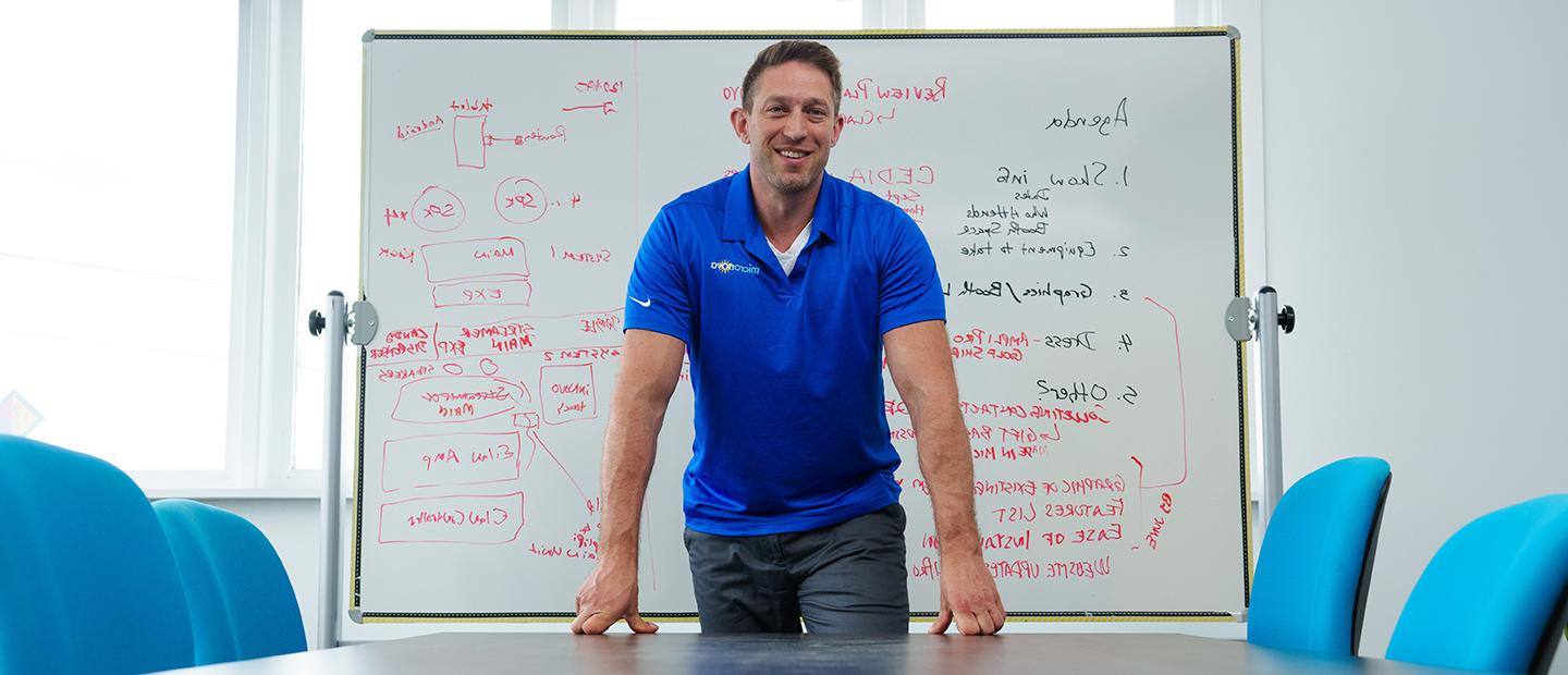 A man standing in front of a white board in a classroom