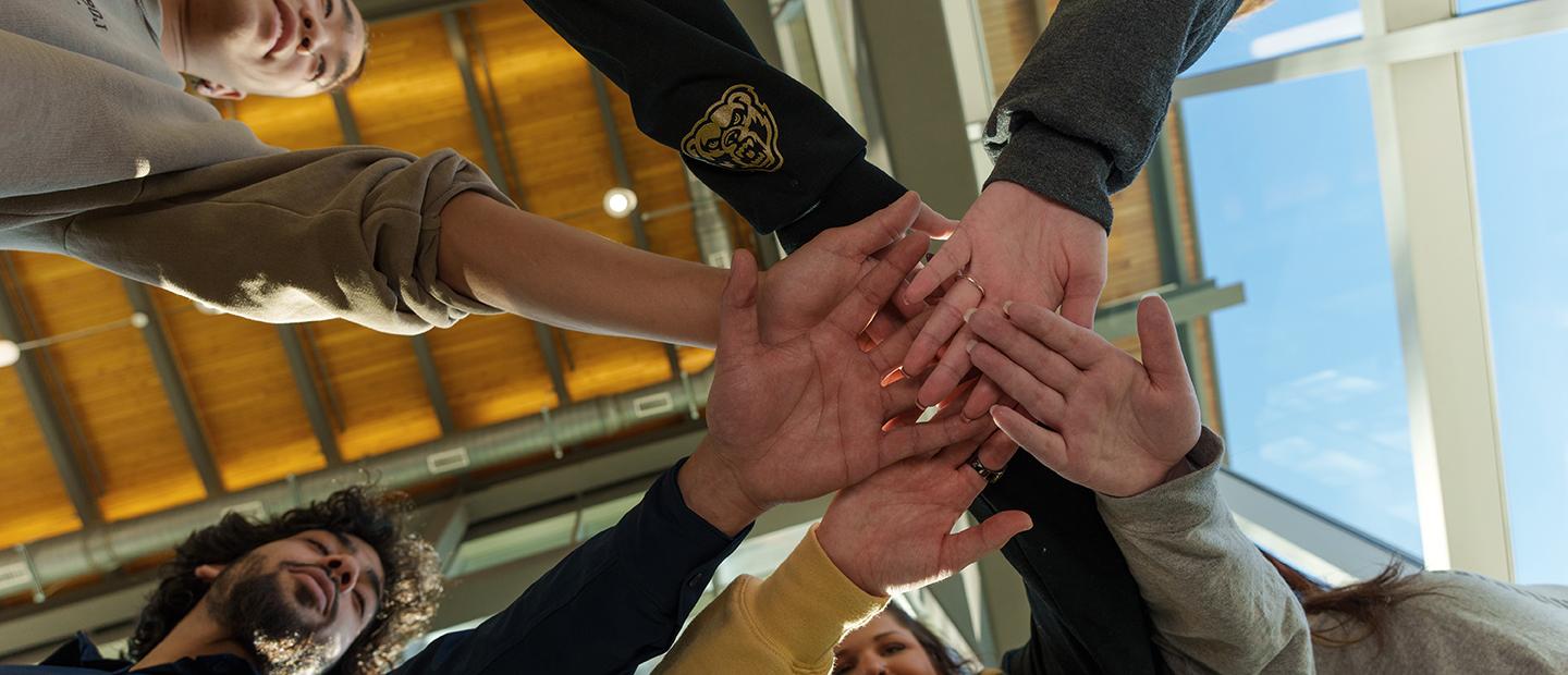 Hands overlapping in the middle of a circle of people